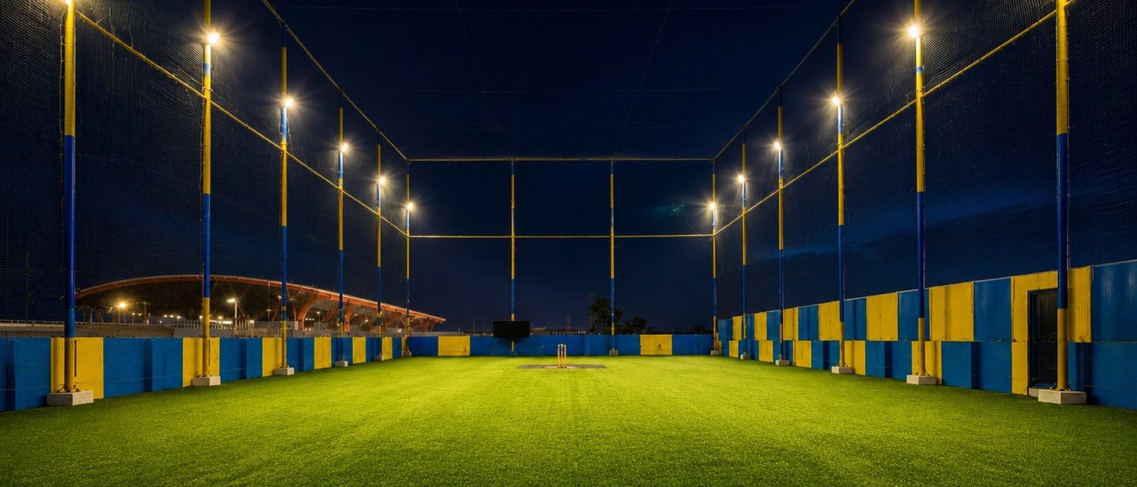 The full court at night with the floodlights on and the pavilion roof behind the boundary
